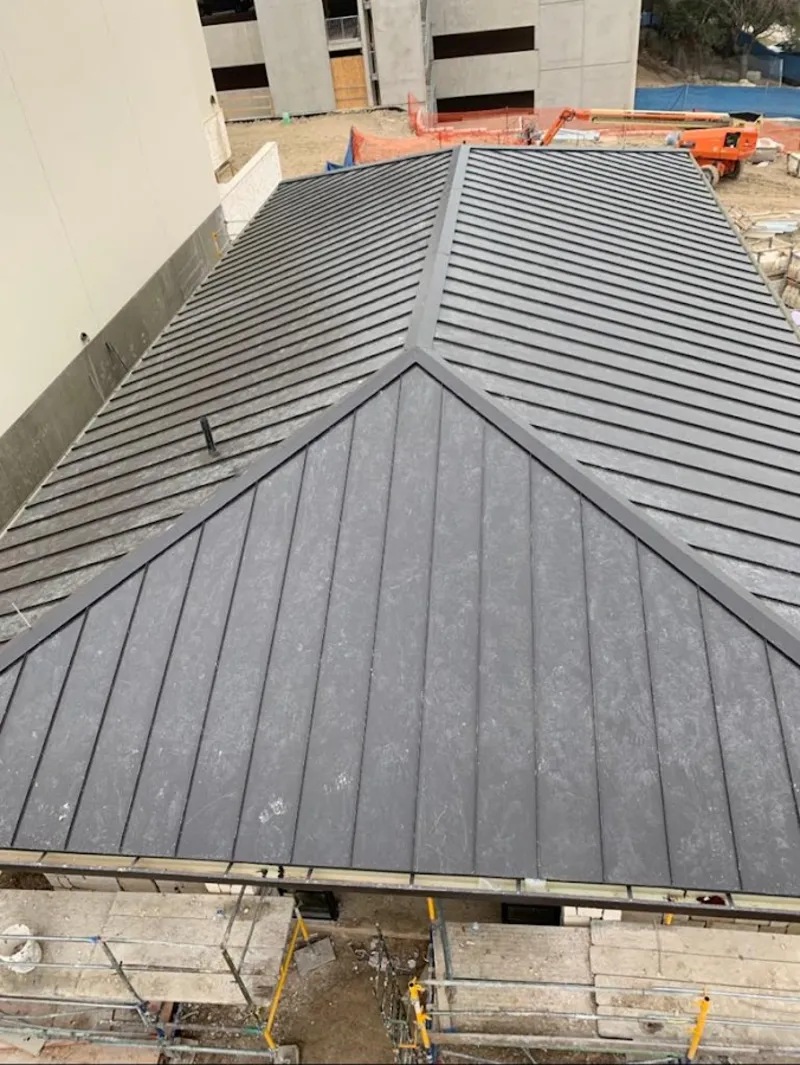 Commercial metal roof construction with crane equipment in Allegan