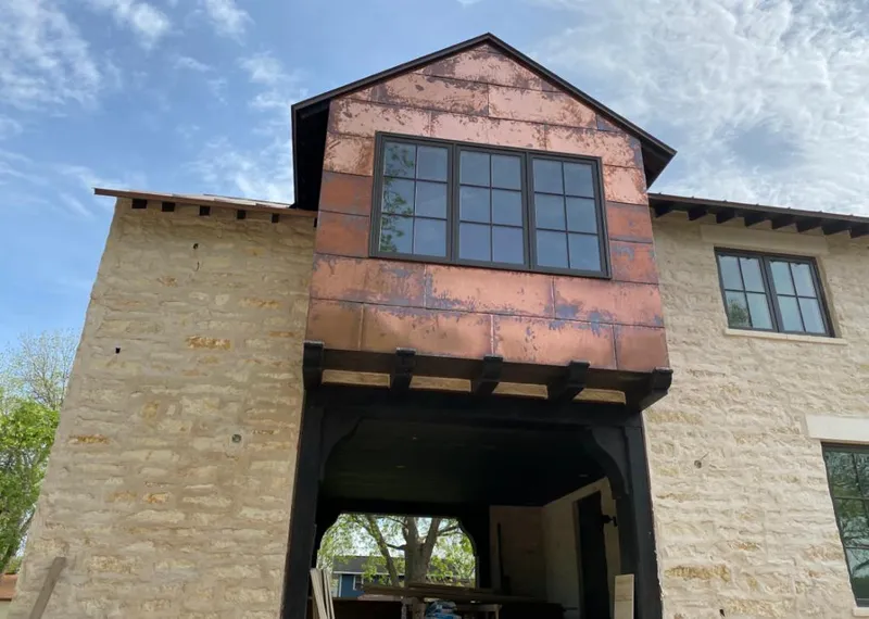 Copper metal panel facade on a stone building for Roof Repair in Allegan